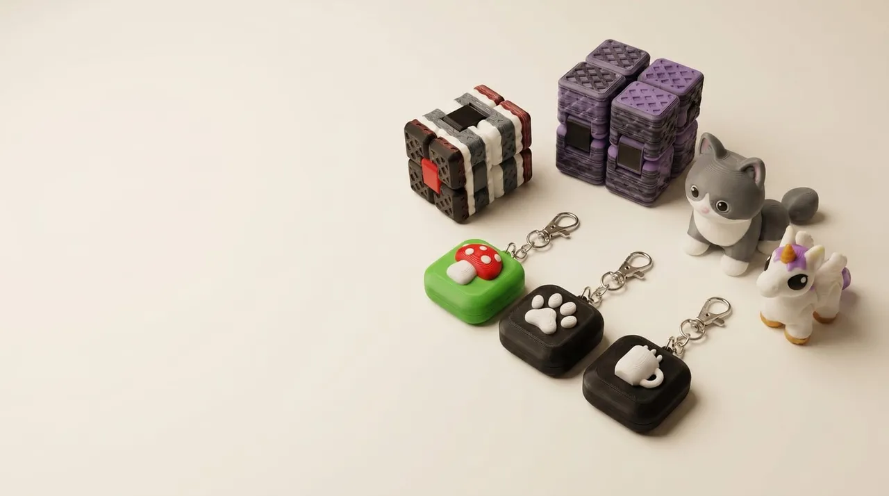 Small-batch QuailWorks fidgets, clickers, and printed creatures arranged on a warm studio surface.